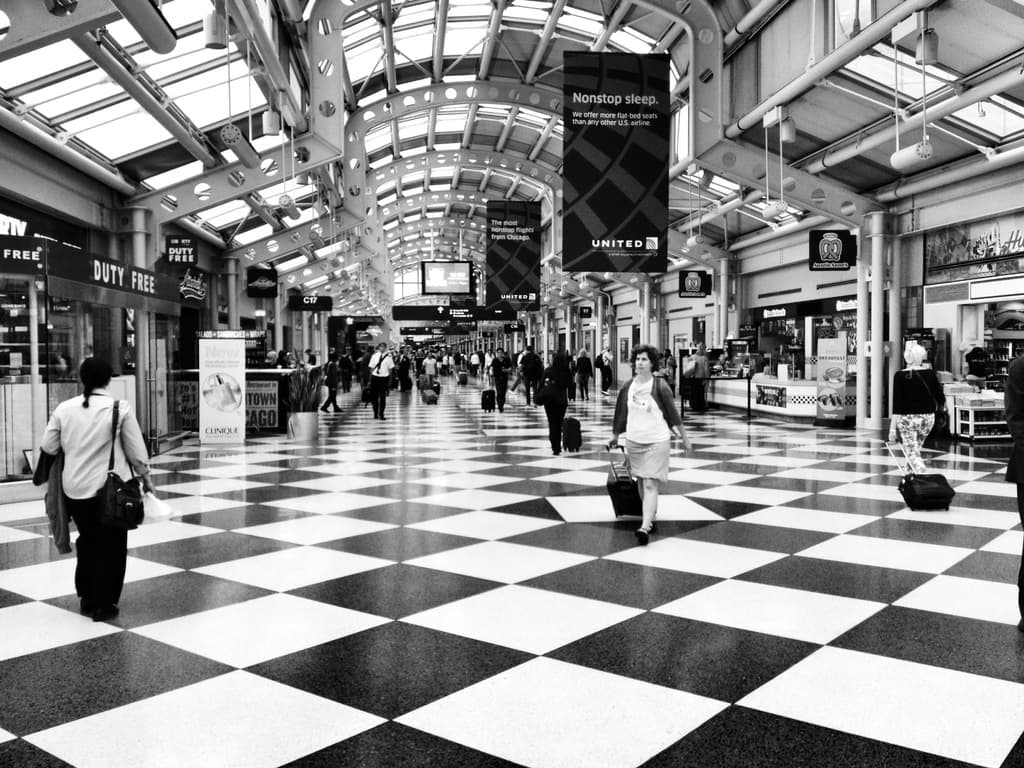 Menschen mit Taschen gehen in einem Gebäude mit Geschäften und Schildern an der Seite.