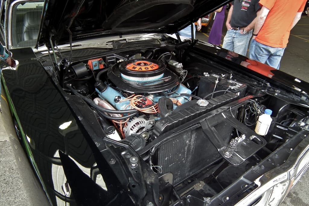 Ein Nahaufnahme-Blick auf Autokühler-Teile mit unscharfen Menschen und einer Straße im Hintergrund.