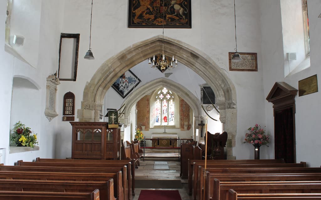 Eine Kircheninnenseite mit Blumenvasen, Bänken, Fotorahmen und Lichtern.