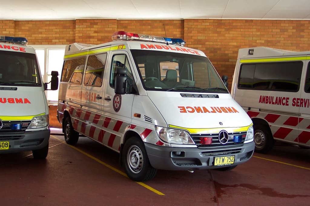 Ein weißer Rettungswagen steht vor einer Backsteinwand.