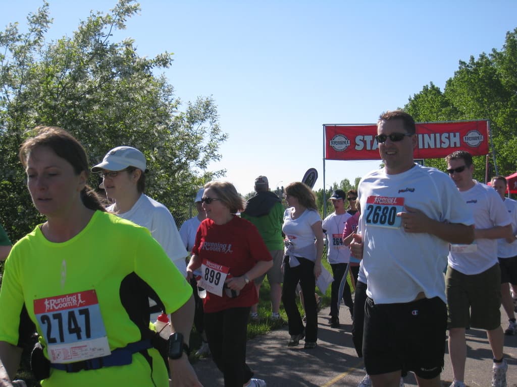 Eine Gruppe von Kindern läuft bei einem Marathon mit einer roten Fahne und Bäumen im Hintergrund.