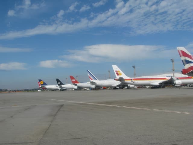 Eine Start- und Landebahn mit wenigen Flugzeugen, Pfählen, Kabeln und einer bewölkten Himmel