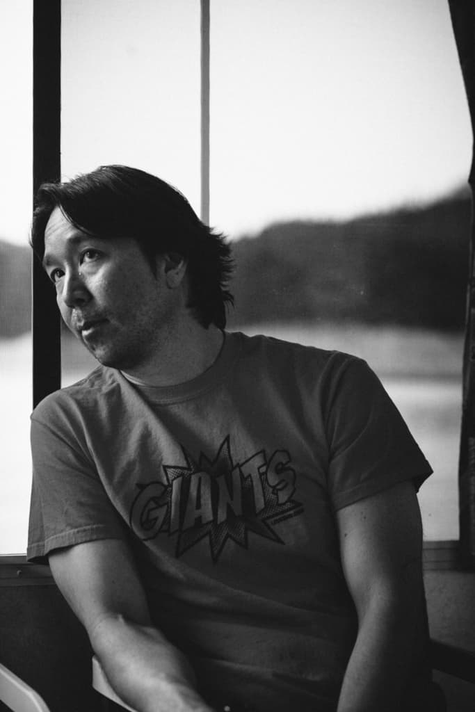 Ein Schwarz-Weiß-Bild eines Mannes in einem T-Shirt mit einem unscharfen Wort im Hintergrund.