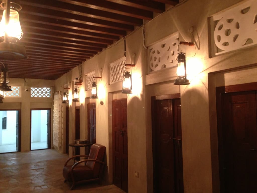 Ein Geb√§ude mit geschlossenen R√§umen, jeder mit einer wandmontierten Lampe und einem Ventilator, ein Stuhl davor und zwei Eing√§nge, mit zus√§tzlichen Lampen, die von der Decke h√§ngen.