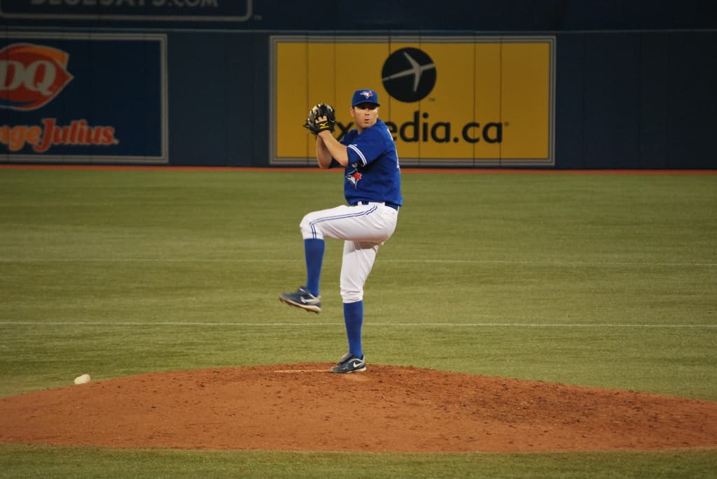 Ein Spieler steht auf dem Boden und hält einen Ball, im Hintergrund eine große Fahne mit Text und Bildern.