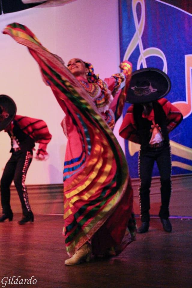 Menschen in Kostümen auf einer Bühne mit einem Vorhang im Hintergrund.