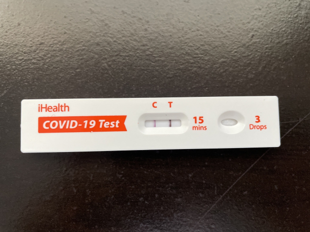 Schwarze Oberfl├Ąche mit einem wei├čen und roten Covid-19-Testthermometer mit Text und Zahlen.