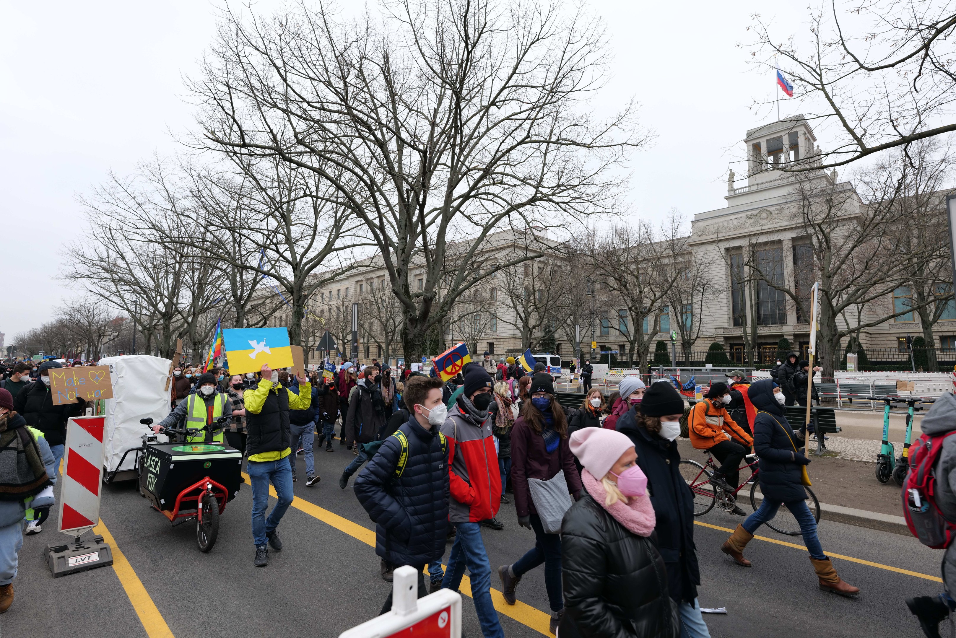 Eine große Gruppe von Menschen marschiert bei einer Demonstration in Washington, D.C. mit Schildern und Fahrrädern die Straße entlang, mit Bäumen und einem Gebäude im Hintergrund und einem klaren blauen Himmel am 21. Januar 2020.