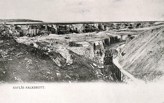 Ein altes Schwarz-Wei√ü-Foto eines Zuges, der in einen Tunnel f√§hrt, mit einer √úberbr√ľckung und Himmel im Hintergrund und Text unten, der 'Kaflas Kalkbrott, das erste Bergwerk in Deutschland' lautet.