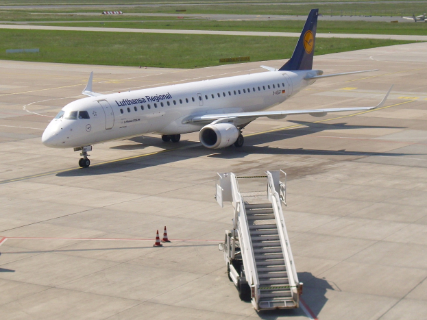 Eine Lufthansa-Regional-Airbus A320-200 auf der Rollbahn am Frankfurter Airport, umgeben von Verkehrskegeln und einem Fahrzeug mit Treppe, mit saftig grünem Gras, Bäumen und einem klaren blauen Himmel im Hintergrund.