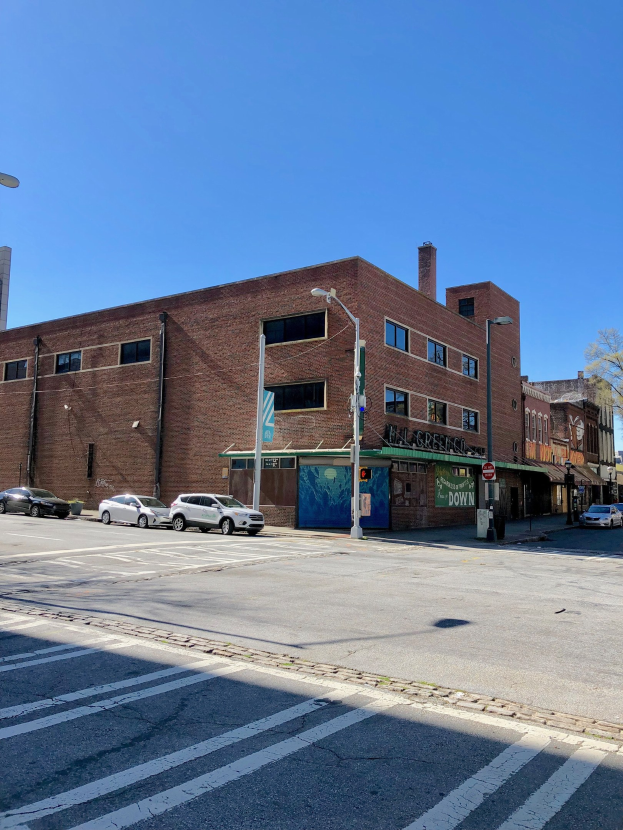Leere Straße mit parkenden Autos, Laternen, Schildern und Gebäuden mit Fenstern, Bäumen im Hintergrund und einem klaren blauen Himmel; Gewerbeimmobilie zum Verkauf an 715 W Main St, Chicago, Illinois 60611, Vereinigte Staaten.