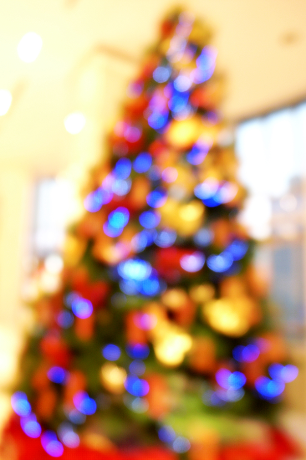 Ein unscharfer Schnappschuss eines drinnen dekorierten Weihnachtsbaums mit Lichtern und Schmuck.