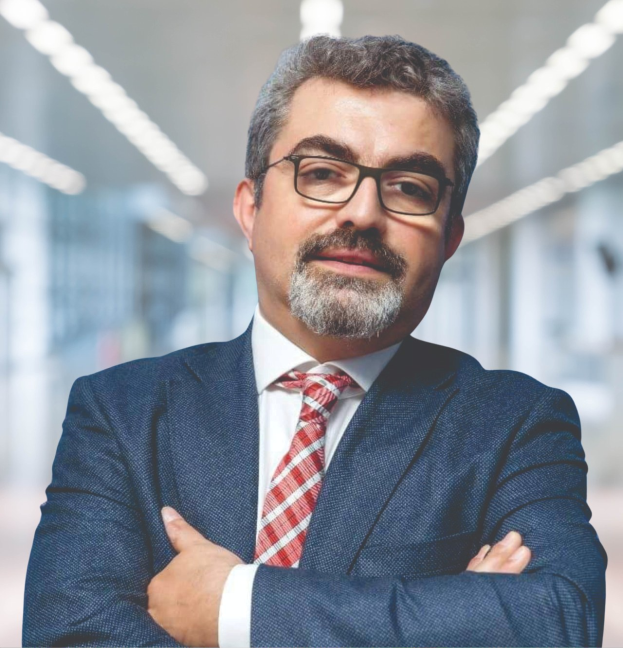 Ein Mann im Anzug und Krawatte mit verschränkten Armen und Brille steht vor einem unscharfen Hintergrund, mit Text unten, der ihn als den neu ernannten Marketingchef identifiziert.