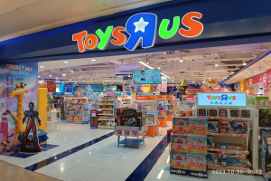 Ein Toys R Us-Laden in einem Einkaufszentrum mit Regalen voller Spielzeug, einem Namensschild mit Text, Deckenleuchten und einem Wasserzeichen in der rechten unteren Ecke.