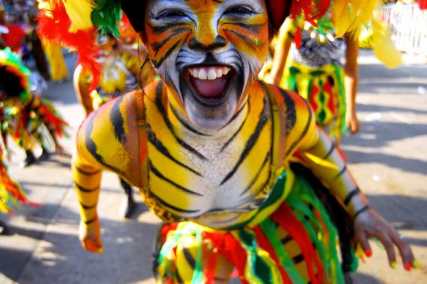 Eine Gruppe von Menschen in bunten Kostümen und Schminke bei einem Karneval, mit einer Frau in einem Tigerkostüm im Vordergrund.