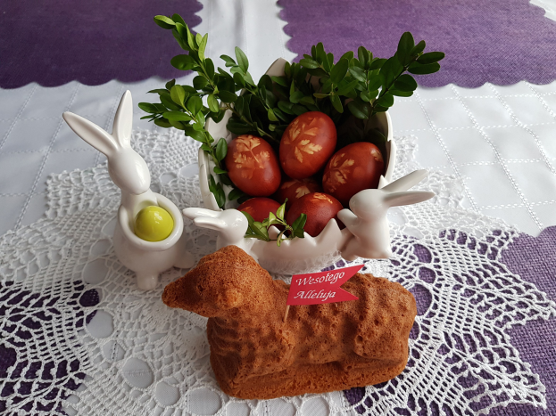 Ein mit einer Decke bedeckter Tisch hält eine Schüssel mit bunten Ostereiern und Osterhasenfiguren darauf.