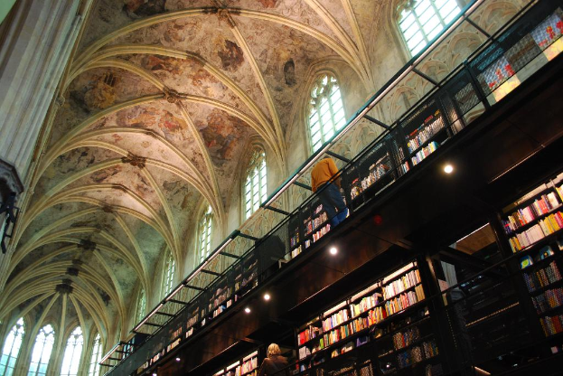 Das Innere eines Gebäudes mit mehreren Menschen, beleuchteten Lichtern und Büchern auf Regalen.