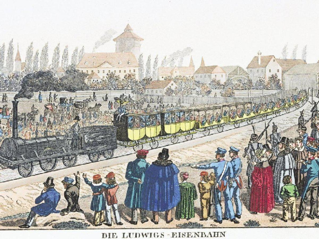Eine Gruppe von Menschen steht um einen Zug auf einem Gleis herum, einige sitzen im Zug und andere auf dem Boden, in der Nähe von Gebäuden und Bäumen, mit Text unten lesend "Ludwigs-Eisenbahn, die erste Bahnstation in Deutschland"