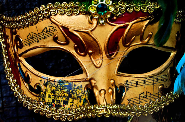 Ein Nahaufnahme eines Faschingsmasken mit Musiknoten, detaillierten Designs und Federn, mit einem unscharfen Hintergrund.