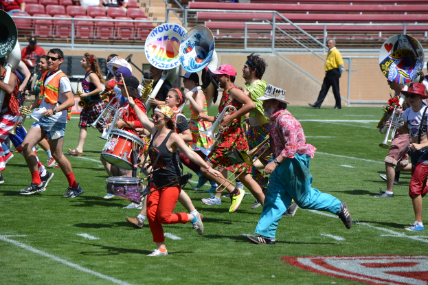 Eine Gruppe von Menschen versammelte sich im Freien mit Musikdrums, verschiedenen Instrumenten, Stühlen, Treppen und einem Zaun im Hintergrund.