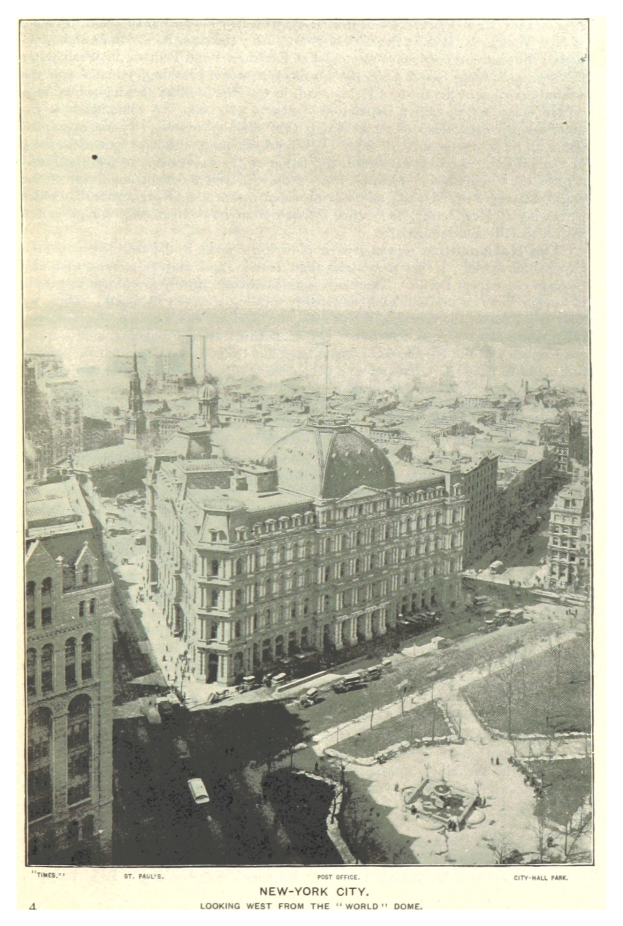 Altes Schwarz-Weiß-Foto einer Stadt mit einem prominenten zentralen Gebäude, kleineren umliegenden Gebäuden, Fahrzeugen auf der Straße und Bäumen, mit Text unten.
