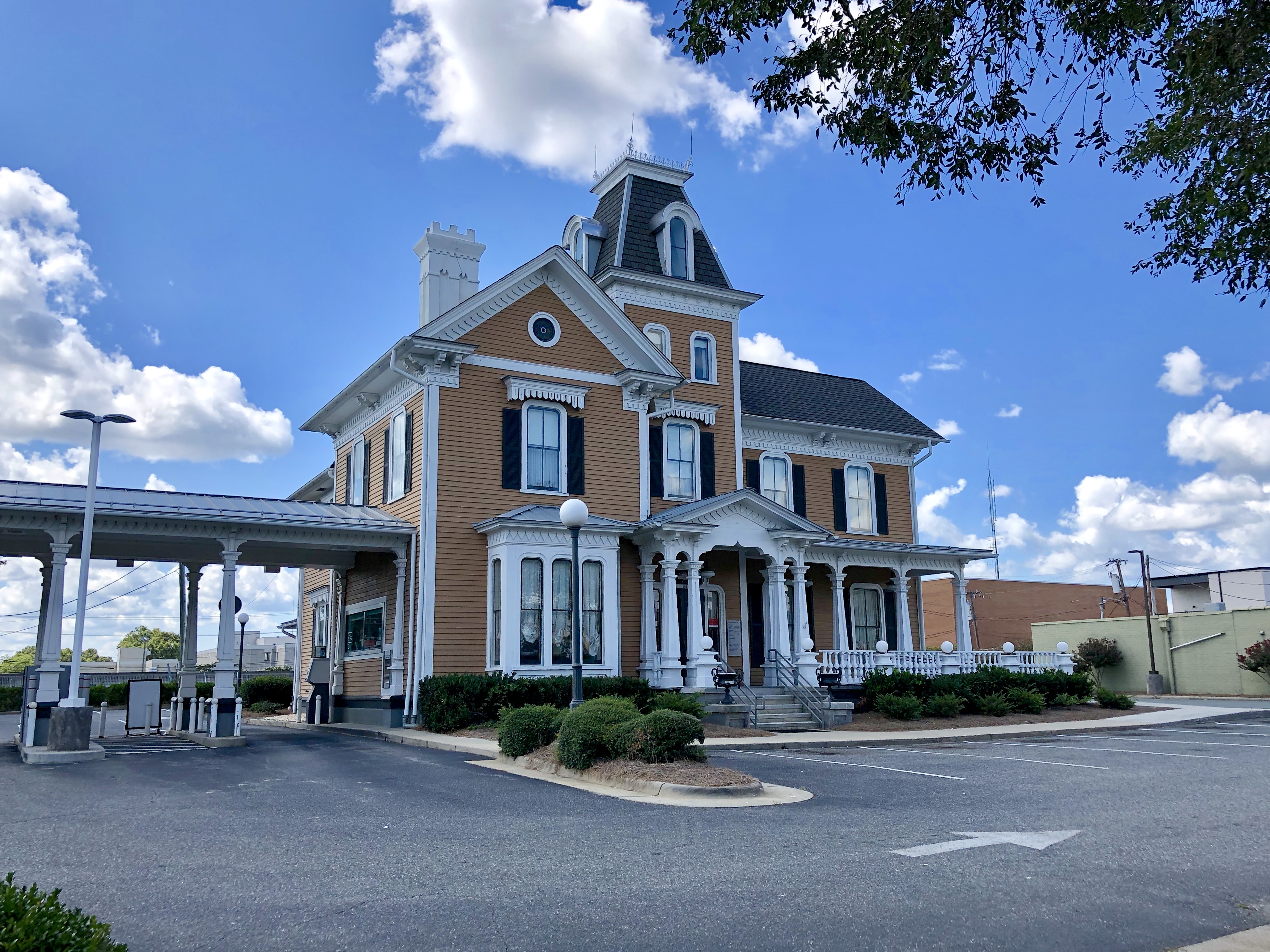 Ein großes gelbes historisches Union Station Gebäude mit einem Uhrenturm, umgeben von Straßenmasten, Straßenlaternen, Kraftfahrzeugen, Sträuchern, Bäumen und einem bewölktem Himmel.