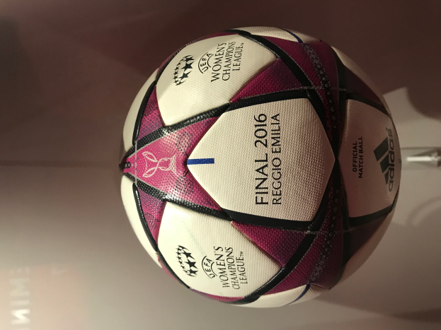 Ein weißer Fußball mit schwarzen und pinken Akzenten liegt auf einem hellen Holztisch und zeigt den Text "UEFA Women's Champions League Final 2016".