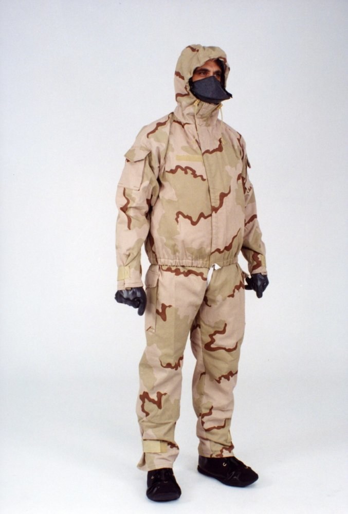 Eine Person in einem Ganzkörper-Schutzanzug mit Kapuze und Maske steht vor einem weißen Hintergrund.