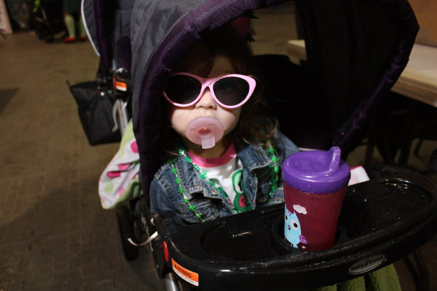 Kind sitzt in einem Laufwagen auf der Straße.