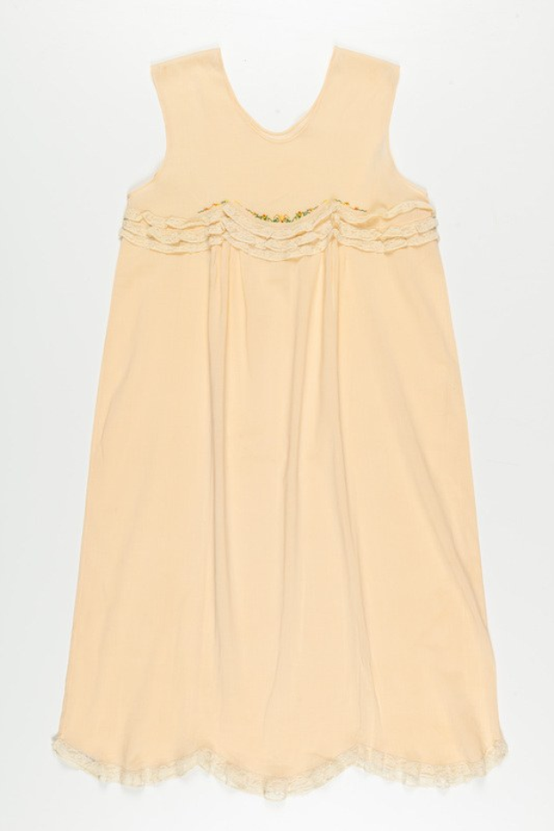 Ein cremefarbenes Nachthemd mit zarter Spitzenborte am Halsausschnitt, aus weichem, leichtem Stoff mit einem dezenten Glanz.