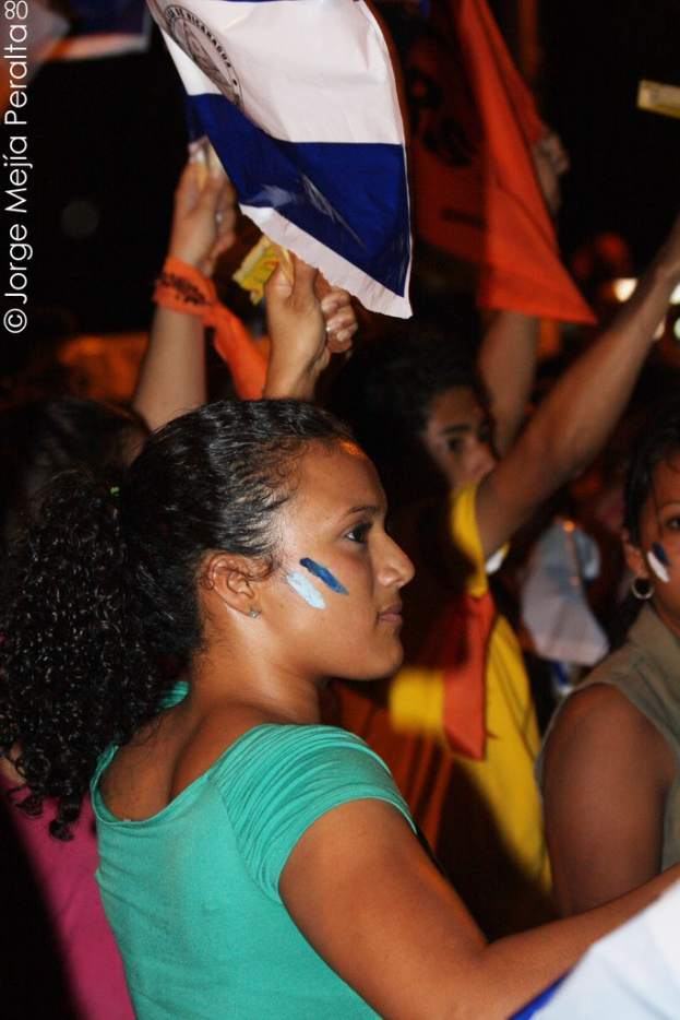 Frauen in grünen T-Shirts bei einer Demonstration, die weiße Schilder halten, mit vielen anderen Mädchen im Hintergrund.