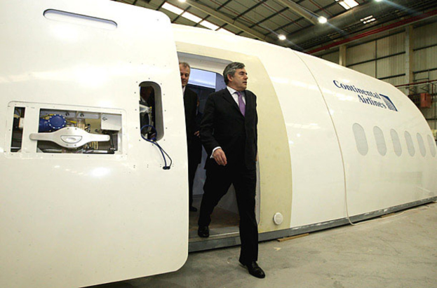 Ein Flugzeugprototyp mit der Aufschrift "Continental Airlines", umgeben von zwei Personen und einer Wand mit Lampen und anderen Gegenständen im Hintergrund.