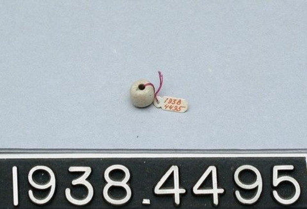 Ein weißes Auto mit einer Nummernschild auf der Rückseite und einem kleinen weißen Objekt mit einer daran befestigten Markierung, auf der '1938 4495' steht.