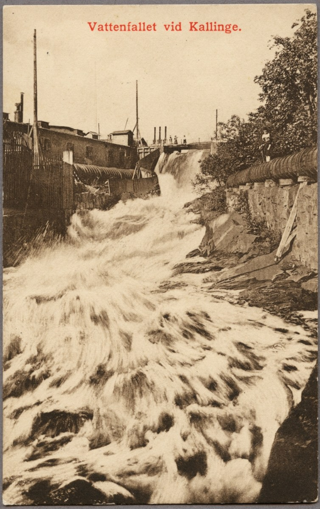 Altes Schwarz-Weiß-Foto eines Flusses mit fließendem Wasser, umgeben von Bäumen, Gebäuden, Strommasten und einem Zaun, mit Text oben drauf.