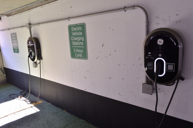 Wandmontierte Ladestationen für Elektrofahrzeuge in einer Tiefgarage mit Informationsschildern darunter.