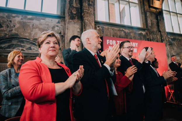 Eine Gruppe von Menschen, die vor einem Publikum jubeln, mit einem Banner im Hintergrund, auf dem steht: "Wir haben die Wahl gewonnen."