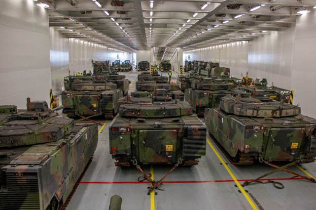 Eine gro├če Militargelandehalle mit Reihen von Militartanks, Wanden an beiden Seiten und Deckenbeleuchtung.