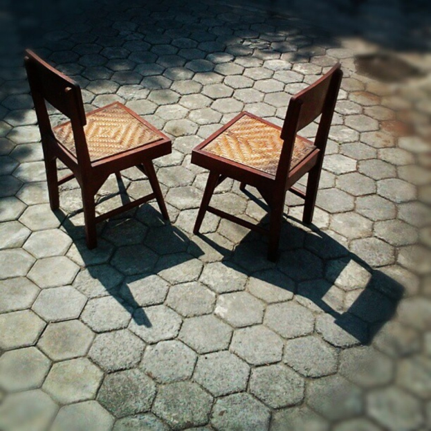 Zwei braune Stühle auf einer Asphaltstra√üe.