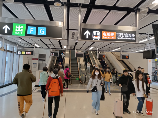 Eine Gruppe von Menschen mit Gepäck geht durch einen Flughafen mit Rolltreppen, Anzeigetafeln, Deckenlampen und Glaswänden im Hintergrund, mit einem Wasserzeichen, das den Flughafen aufgrund der Coronavirus-Pandemie als geschlossen kennzeichnet.