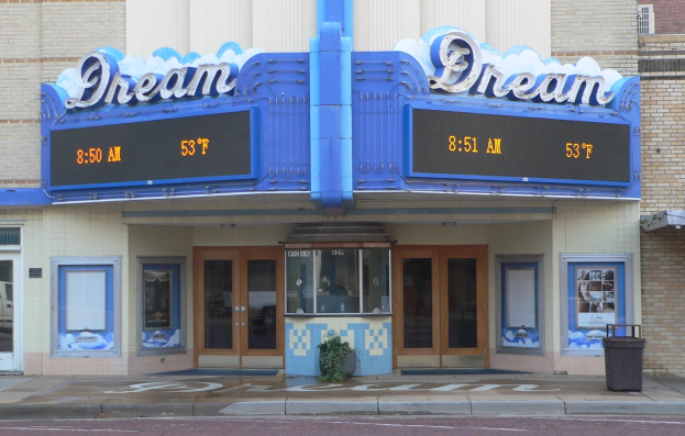 Außenansicht des Dream Theaters in St. Louis, Missouri, mit Glasfenstern und -türen, einer Schautafel, einem Mülleimer, einem Topf mit einer Pflanze und einer Straße unten.