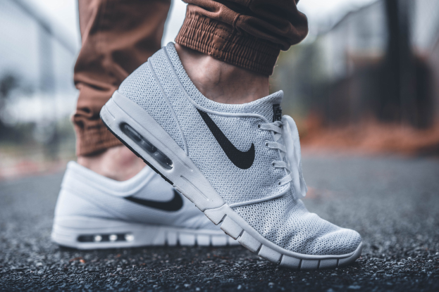 Eine Person trägt Nike SB Stefan Janoski Max Schuhe in Wolf Grau/Schwarz-Weiß, mit einem unscharfen, träumerischen Hintergrund.