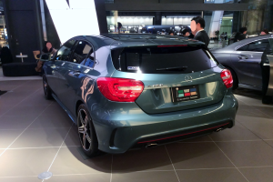 Ein Mercedes-Benz A-Klasse-Hatchback mit glänzender schwarzer Lackierung und Chromakzenten, das auf der IAA in Frankfurt gezeigt wird, umgeben von Menschen.