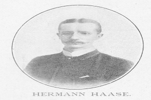 Schwarzes und weißes Portr├Ąt des deutschen Komponisten und Pianisten Hermann Haase in einem Anzug mit Schnurrbart, ernster Miene und deutschem Text unten.
