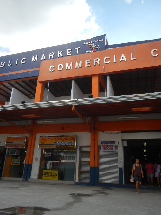 Öffentlicher Markt mit Menschen vor dem Gebäude unter einem sichtbaren Himmel.