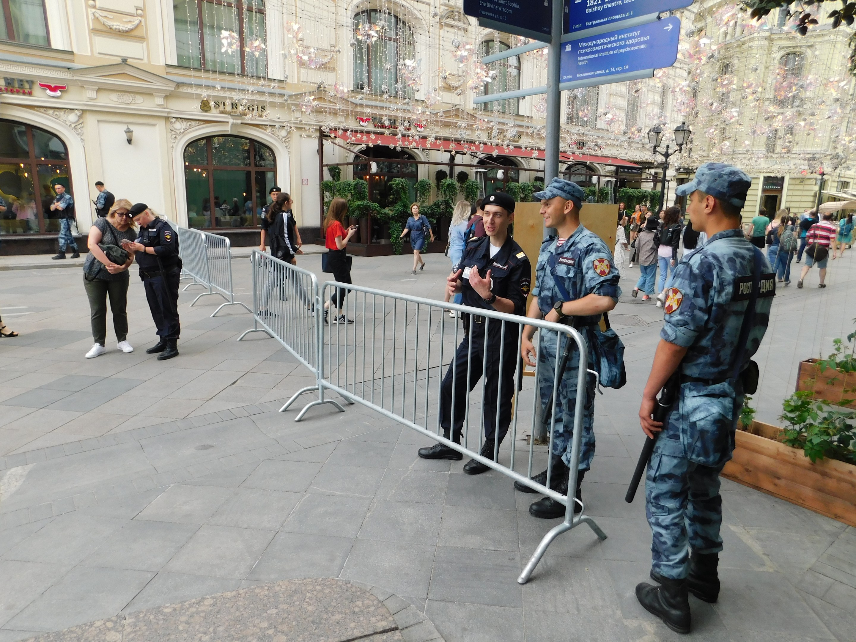 Polizeibeamte in Uniform stehen hinter Absperrungen und blicken einer Menge entgegen, von denen einige Mützen tragen und Waffen tragen, während sie eine Anti-Terror-Operation in Wien, Österreich, durchführen.