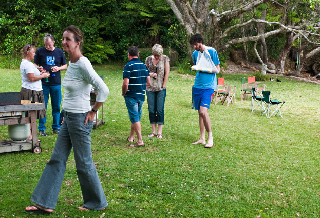 Eine Gruppe von Menschen, die in einer Outdoor-Umgebung an Tischen und Stühlen steht und geht, umgeben von Bäumen und Gras.