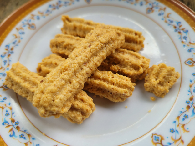 Ein Teller mit Cheetos und goldbraunen, knusprigen Churros in einem kreisförmigen Muster auf einem Tisch.