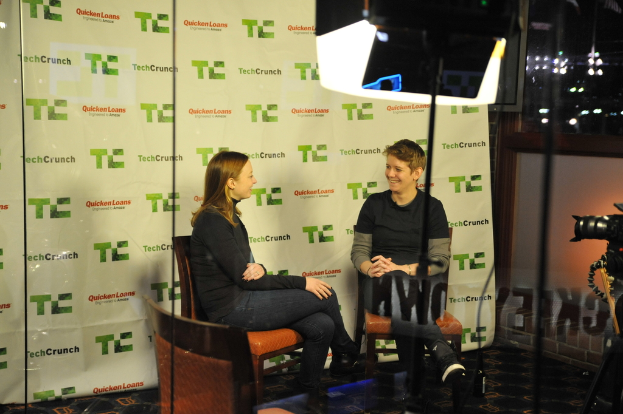 Ein Mädchen und ein Junge, die auf Stühlen sitzen und miteinander sprechen, mit einer Kamera im Vordergrund.