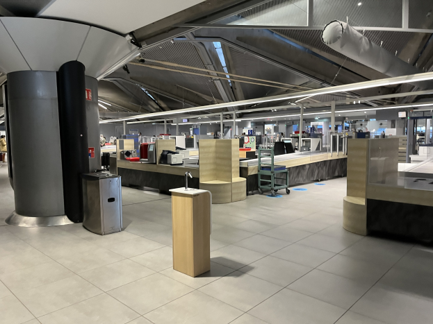 Ein geräumiger Raum im neuen Terminal des Frankfurter Flughafens, gefüllt mit Tischen, Stühlen, Säulen und diversen Gegenständen, mit einigen wenigen Menschen und der Decke sichtbar.