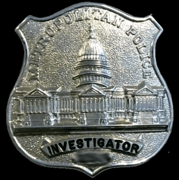 Ein silbernes Polizeischild mit der Aufschrift "Investigator" auf einem weißen Hintergrund.